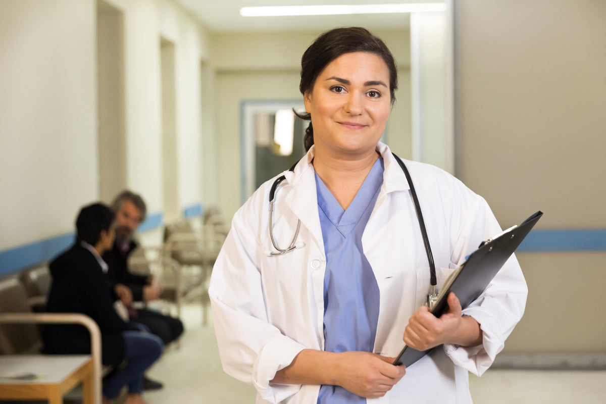 Smiling nurse holding a clipboard in a hospital hallway